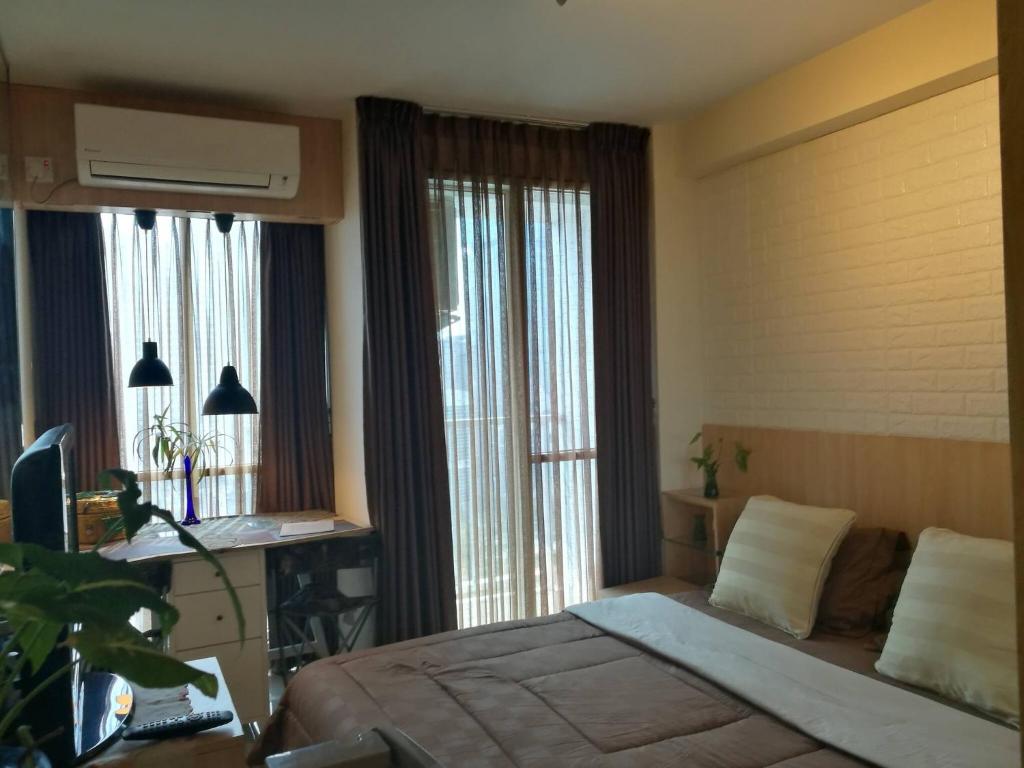 una camera con letto, scrivania e finestre di Pleasant@tifolia , 1br, New Room In Kelapa Gading a Giacarta