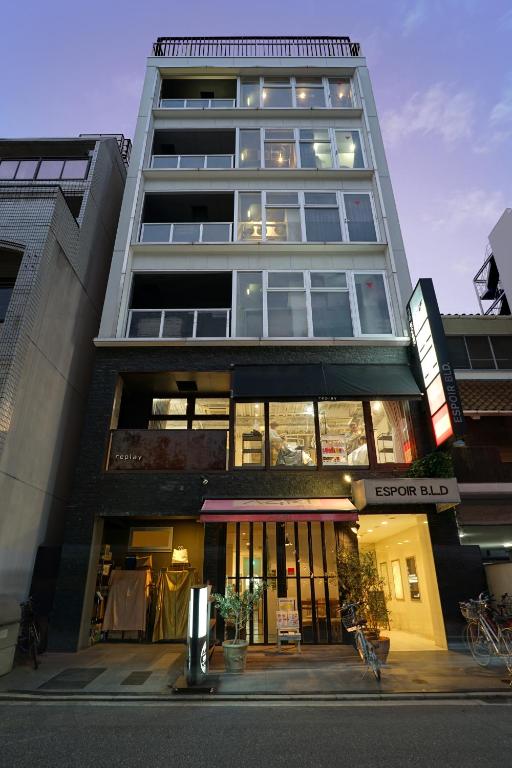 un edificio alto con una tienda delante en Santiago Guesthouse Hiroshima, en Hiroshima