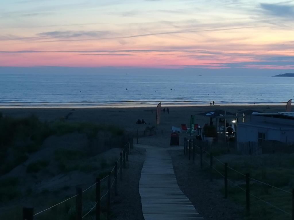 una pasarela que conduce a la playa al atardecer en GUEST HOUSE groupe et Famille, en Saint-Paimboeuf