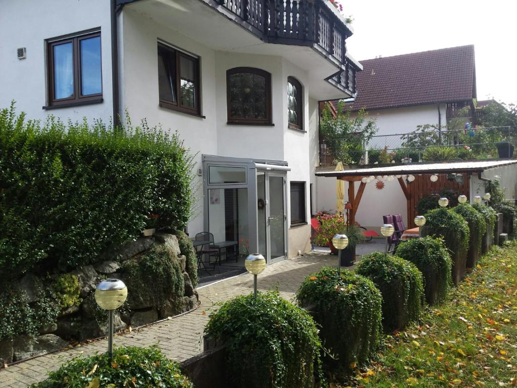 una casa blanca con un patio con arbustos en Ferienwohnung Kiruga en Kippenheim