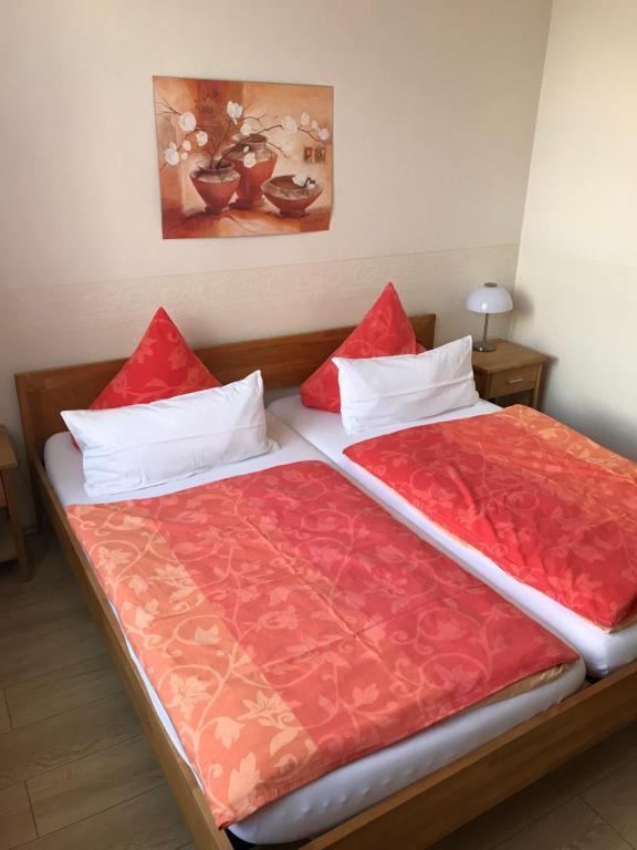 Bett mit roten und weißen Kissen in einem Zimmer in der Unterkunft Pension Auszeit in Bad Neuenahr-Ahrweiler