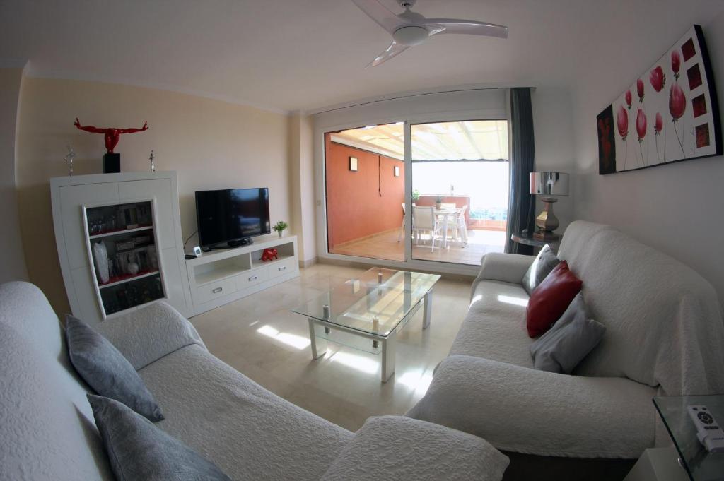 een woonkamer met een bank en een glazen tafel bij Penthouse Patio de doña Julia in Casares