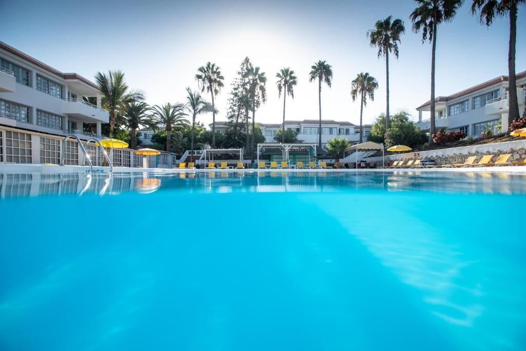 una piscina en un complejo con palmeras en Fuentepark Apartamentos en Corralejo