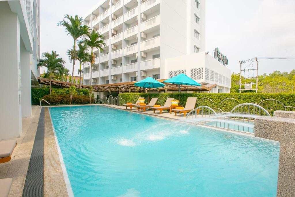 a swimming pool with chairs and umbrellas next to a building at Recenta Phuket Suanluang in Phuket Town