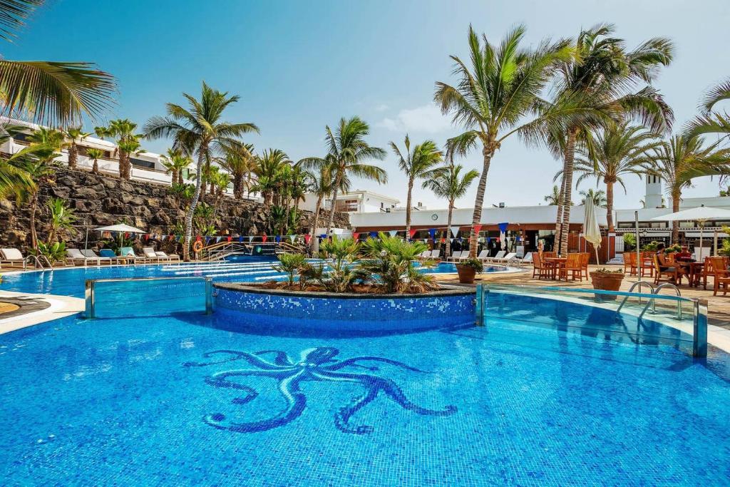 a pool at a resort with palm trees at Apartamentos Temisa in Puerto del Carmen