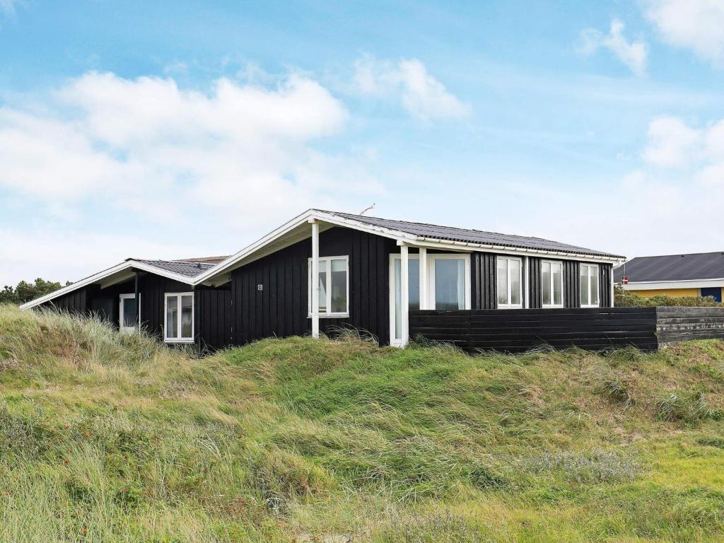 a black house sitting on top of a hill at 7 person holiday home in L kken in Løkken