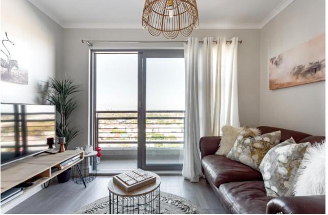 a living room with a couch and a large window at The Paragon Explore Cape Town from a Stylish Home in Cape Town