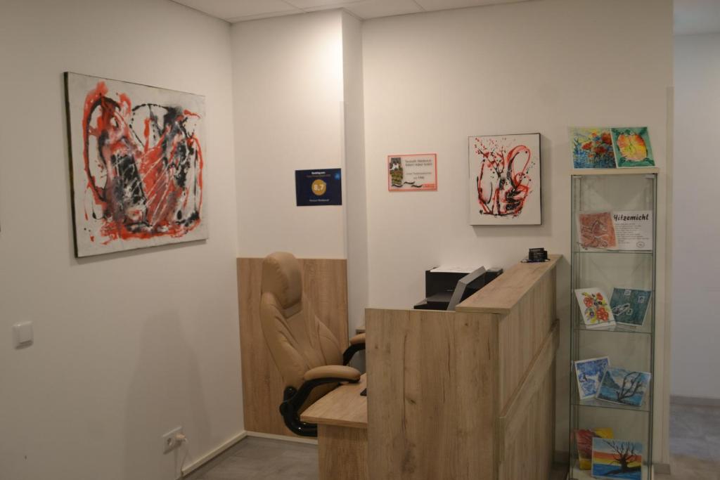 a office with a desk and a chair and paintings at Pension Waldesruh in Linz