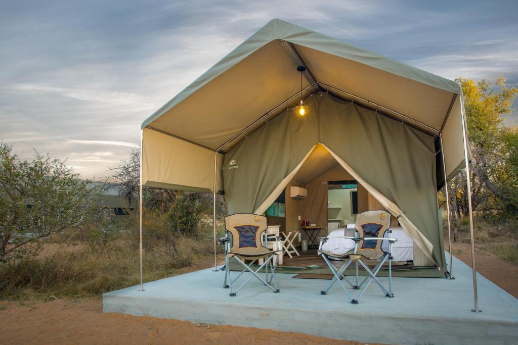 KlipdriftLittle Mongena Tented Camp的帐篷配有椅子和一张床