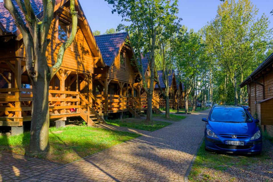 ein blaues Auto, das vor einem Holzgebäude parkt in der Unterkunft Ośrodek Wypoczynkowy Neptun in Władysławowo