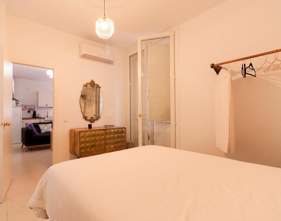 ein weißes Schlafzimmer mit einem Bett und einem Spiegel in der Unterkunft Apartamento - Casa Habanera in Cádiz