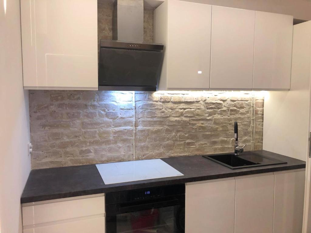 kuchnia z białymi szafkami i czarnym zlewem w obiekcie Apartament 100 Apartamenty No 1 Ogród w Centrum w Szczecinie