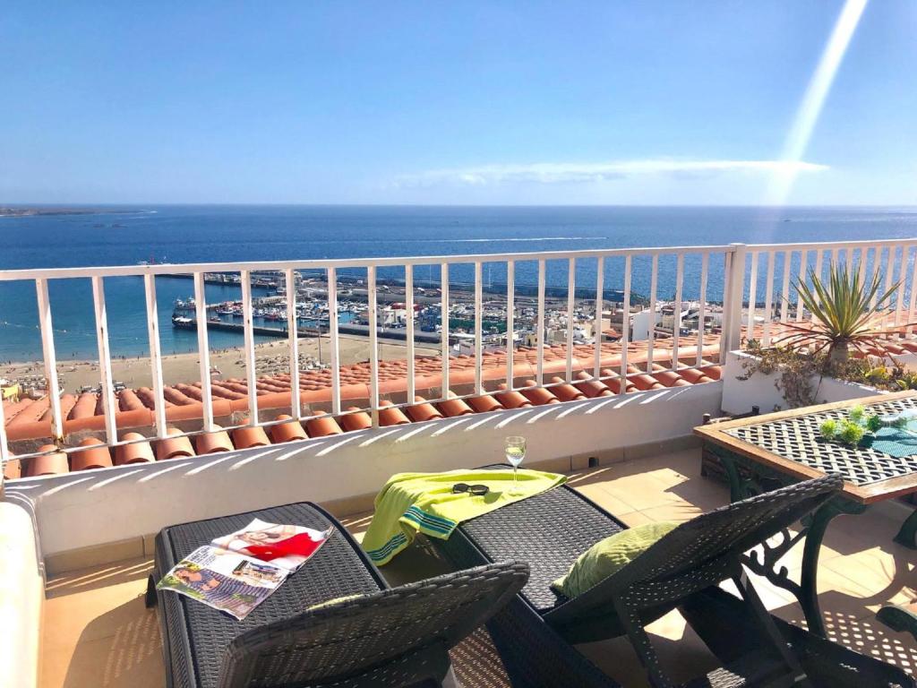 a balcony with chairs and a table and the ocean at Impresionantes vistas al mar en Cactus Blanco in Los Cristianos