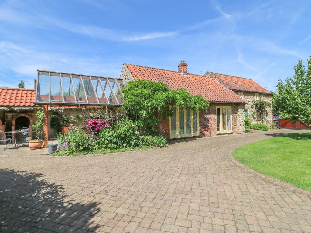 a brick house with a glass roof on a driveway at Forge Cottage in Gainsborough