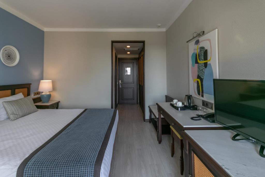 a bedroom with a bed and a desk and a television at Lara Park Hotel in Antalya