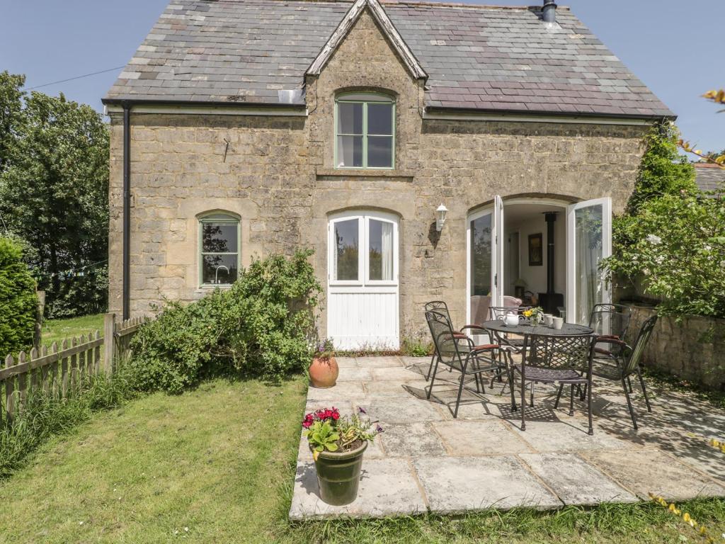 a stone house with a table and chairs in the yard at The Coach House in Shepton Mallet