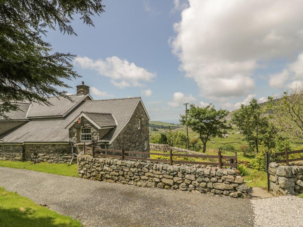 ein Steinhaus mit einer Steinmauer und einem Zaun in der Unterkunft The Stable Cottage in Llanbedr