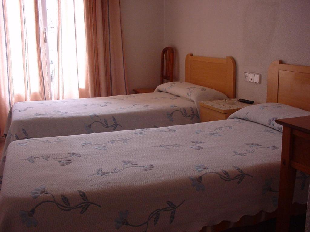 a room with three beds and a window at Hostal Casanova in Madrid