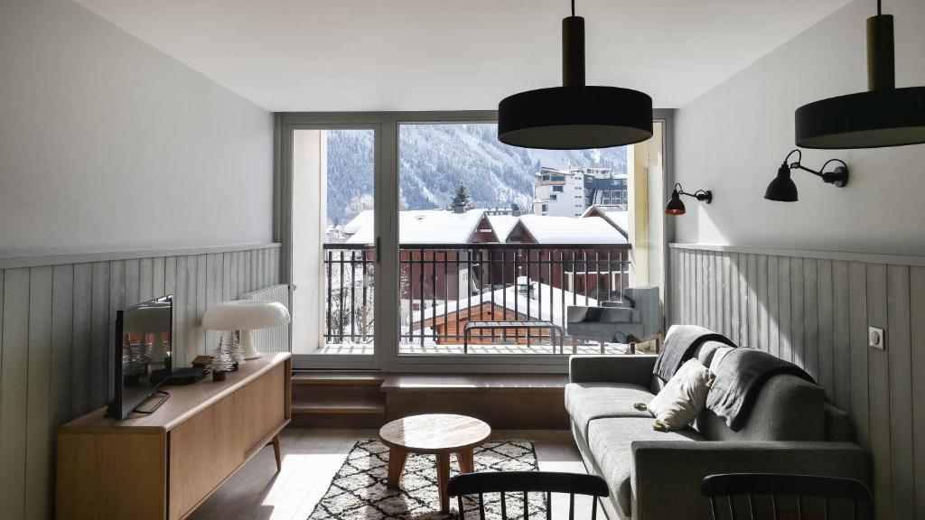 uma sala de estar com um sofá e uma varanda em Appartement La Vallée Blanche avec parking gratuit em Chamonix-Mont-Blanc