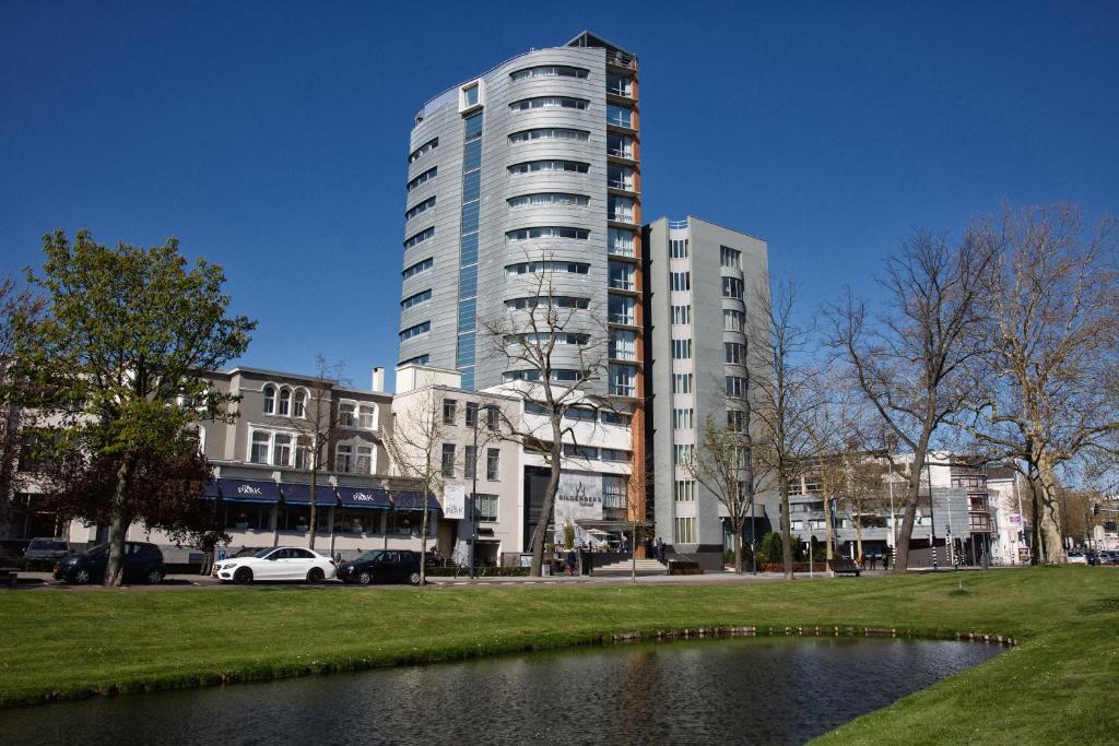 ein hohes Gebäude in einer Stadt mit einem Teich in der Unterkunft Bilderberg Parkhotel Rotterdam in Rotterdam