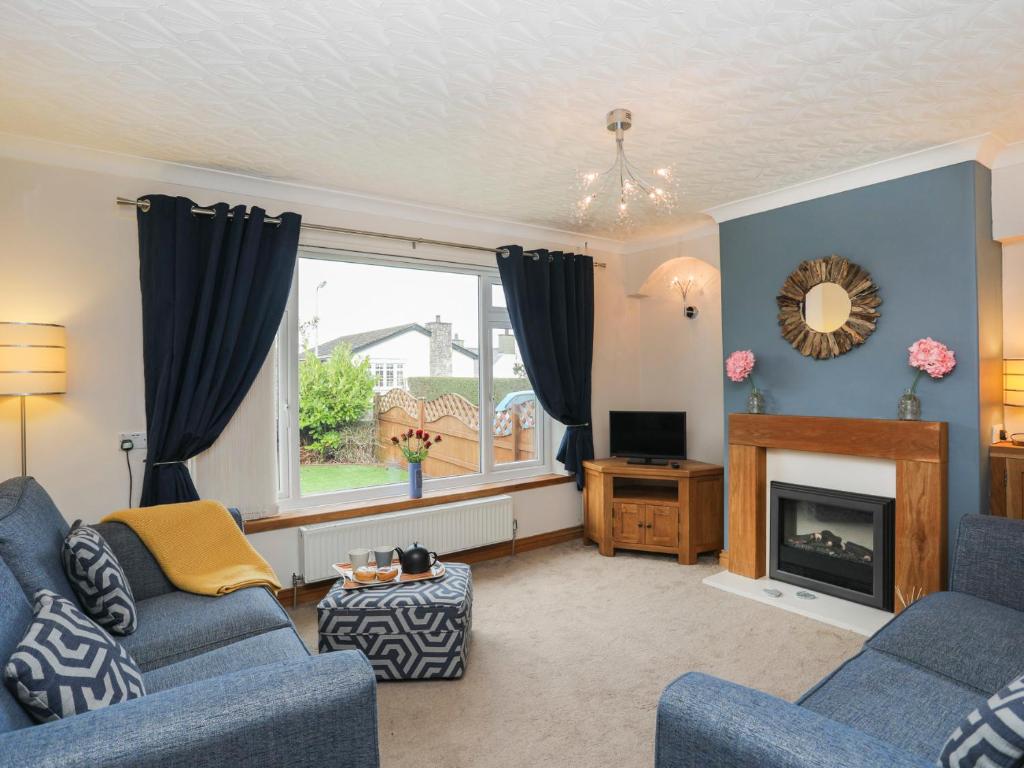 sala de estar con 2 sofás azules y chimenea en Bay View - Benllech en Benllech