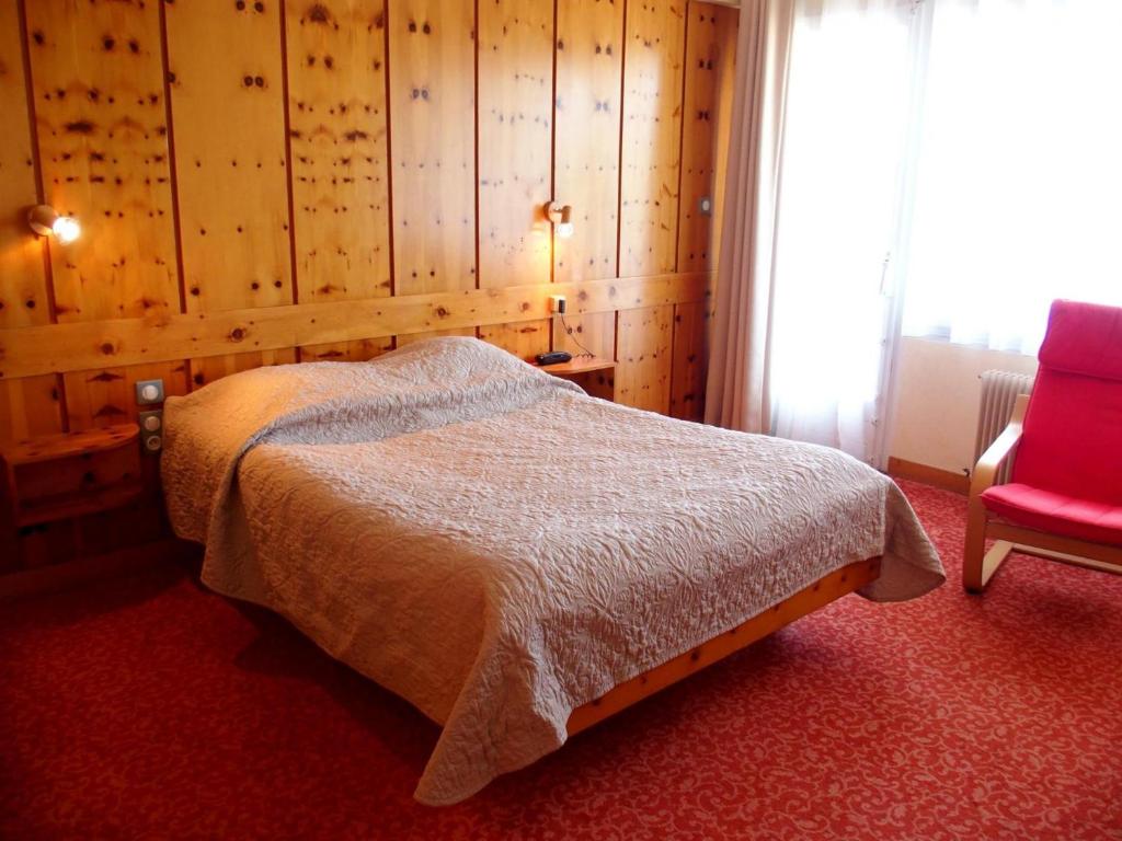 a bedroom with a bed and a red chair at Hôtel des Vosges in La Petite-Pierre