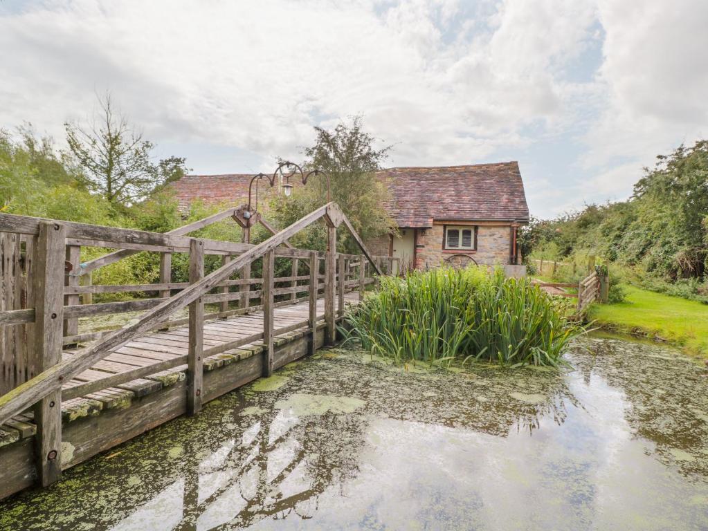 a wooden bridge over a pond in front of a house at Jackdaw's Roost in Gloucester