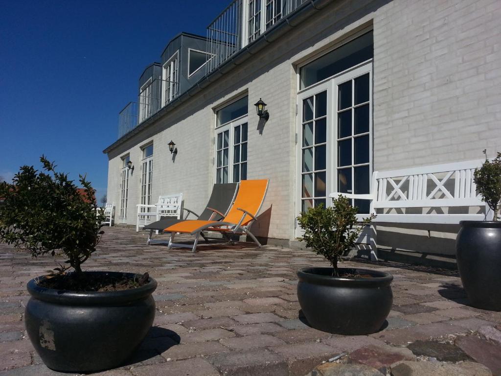 a patio with chairs and potted plants in front of a building at Roskilde B&B in Gadstrup