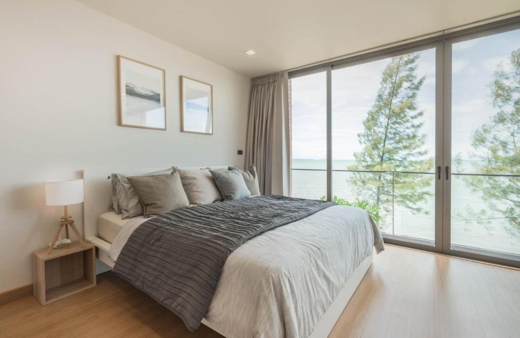 a bedroom with a bed and a large window at Sandbox Beachfront Villa 3 in Ban Krathing Lai