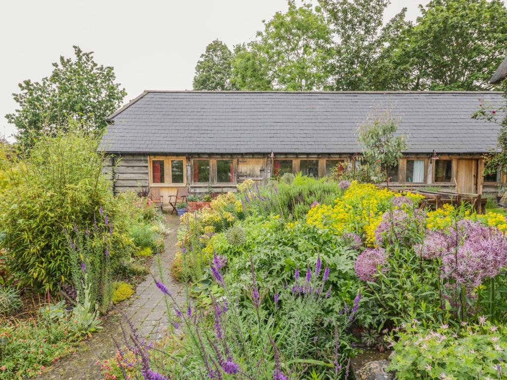 a house with a garden with flowers in front of it at Ryepiece Cottage in Stratford-upon-Avon