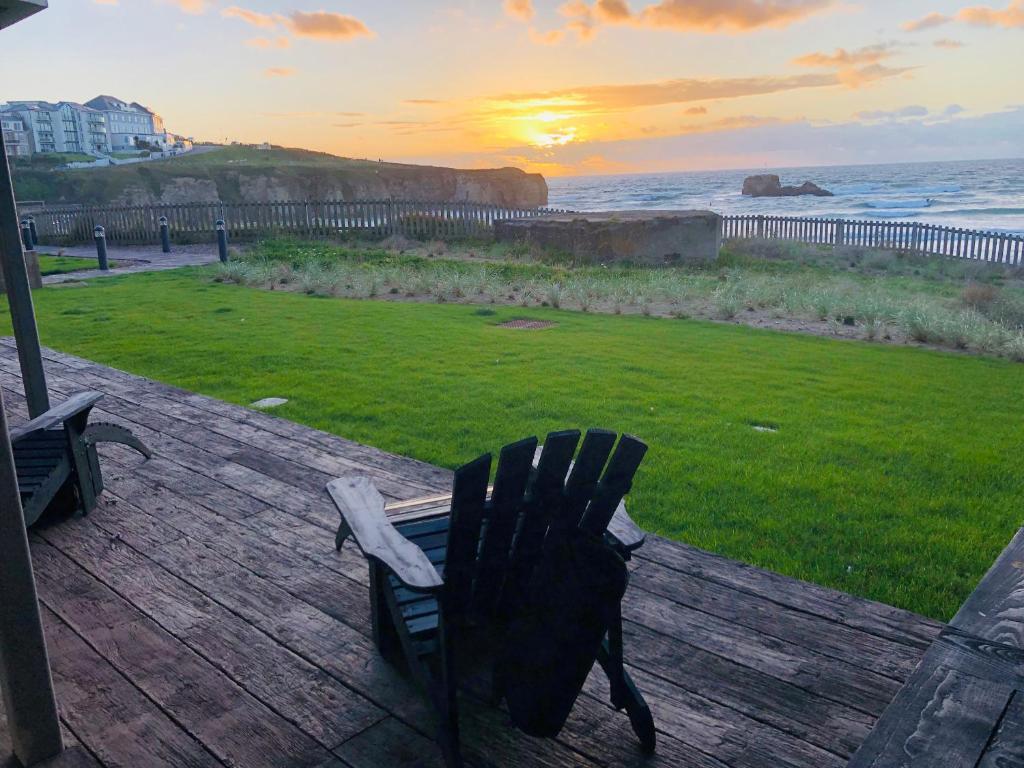 a bench on a deck with a view of the ocean at Chapel Rock View, The Dunes in Perranporth