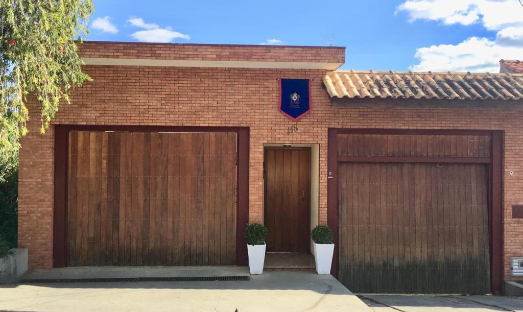 un edificio de ladrillo con dos garajes y dos puertas en Pousada Casa de Bragança, en Bragança Paulista