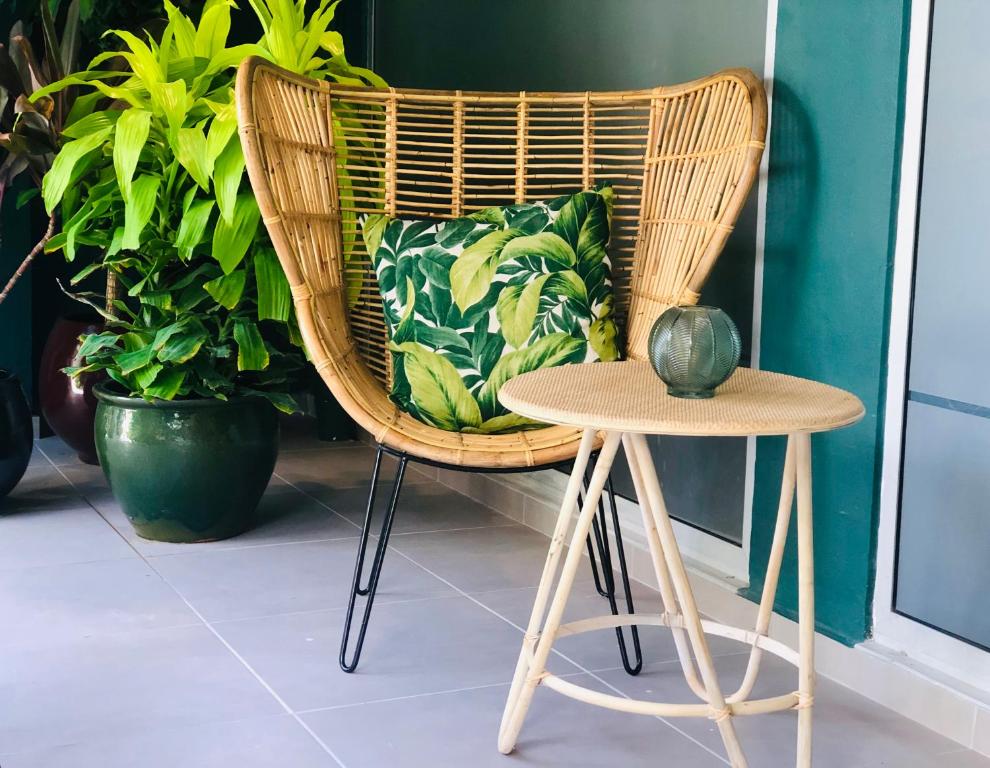 a wicker chair and a table with a vase on it at Centr'Hotel in Marigot