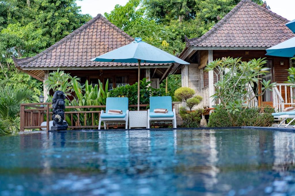 ein Resort mit einem Pool mit 2 Stühlen und einem Sonnenschirm in der Unterkunft Bali Nusa Cottage in Nusa Lembongan