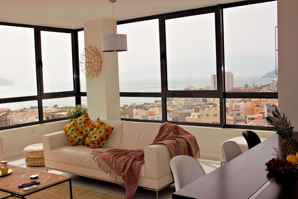 a living room with a couch and large windows at Kasa Imbondeiro in Mindelo