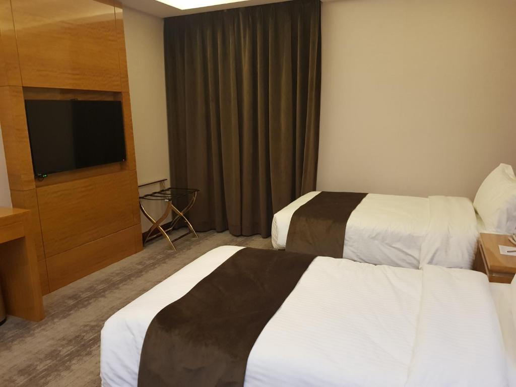 アンマンにあるGloria Hotelのベッド2台と薄型テレビ付きのホテルの部屋