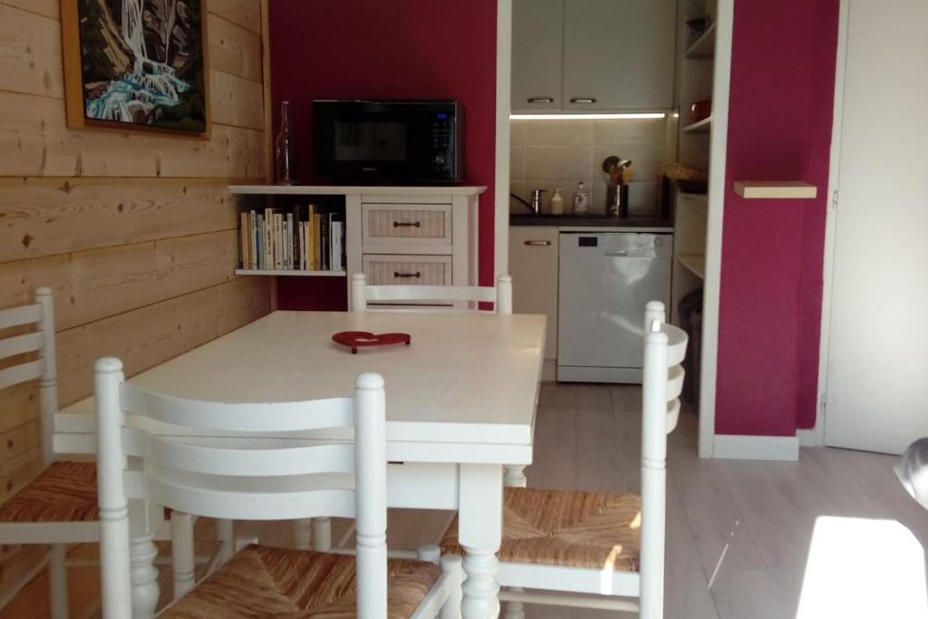 cocina con mesa blanca con sillas y TV en Camp de base, en Le Bourg-dʼOisans