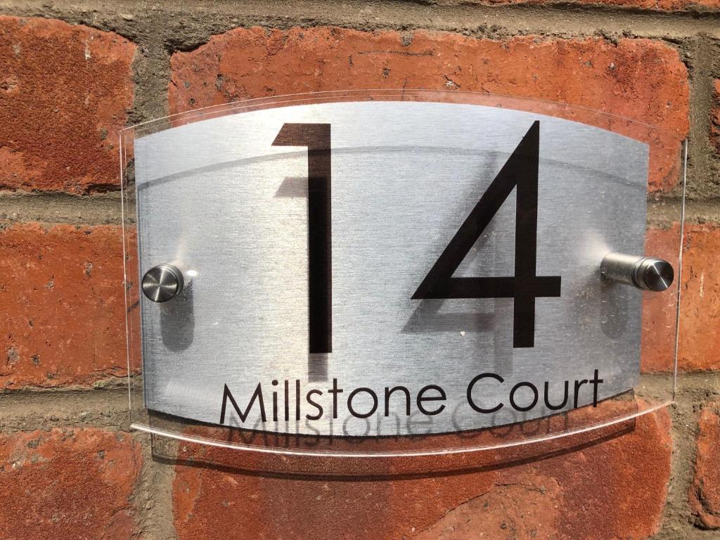 a metal clock on a brick wall with the number four at 14 Millstone Court in Portstewart