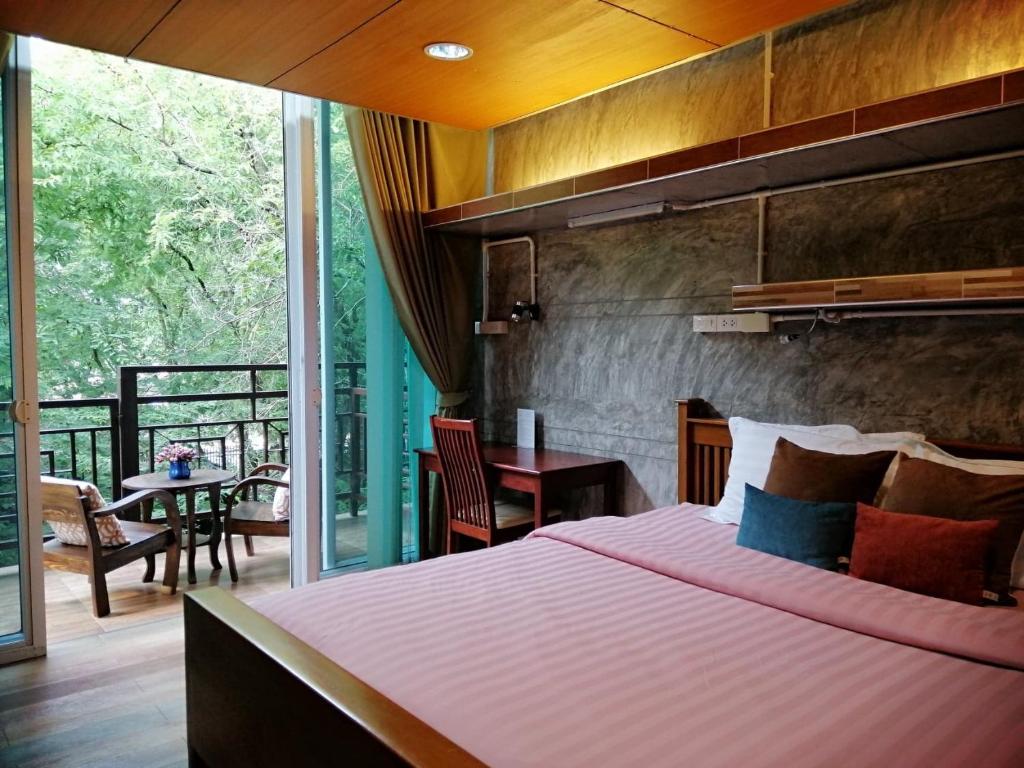 a bedroom with a large bed and a balcony at Loei Huen Hao Hug Home&Resort in Loei