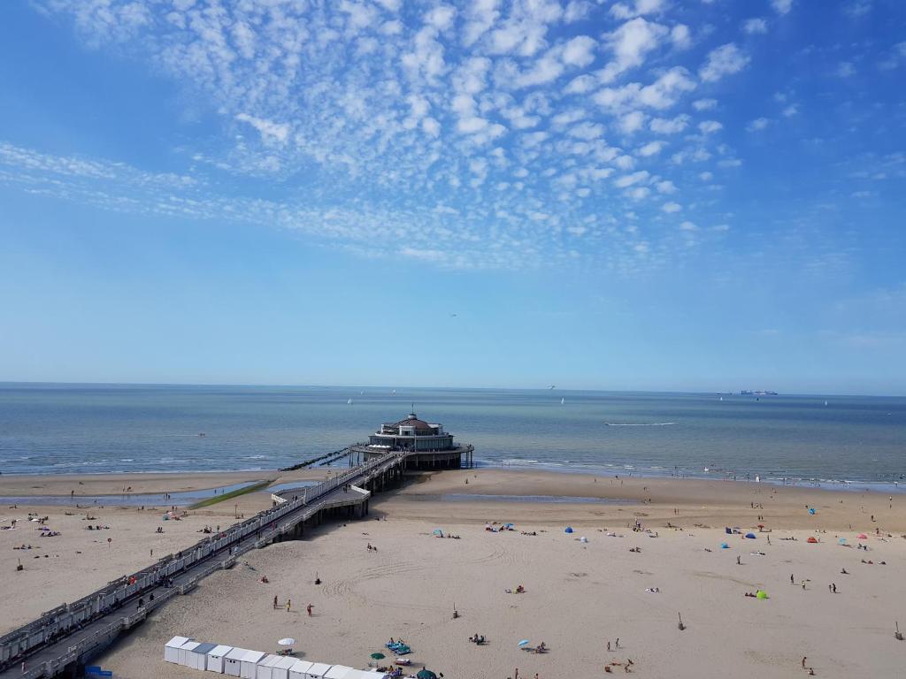 a beach with people on the sand and a pier at Beautiful Top Floor Seaview Studio Apartment B'berge-Bruges in Blankenberge