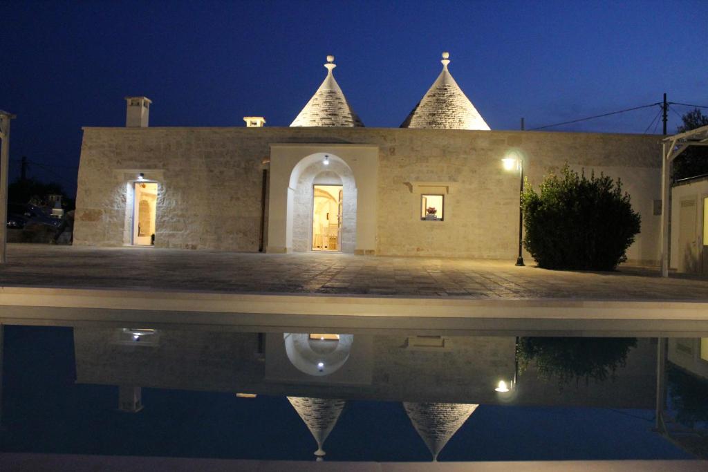 a building with a reflection in the water at night at TRULLI COLIBRI' in Locorotondo