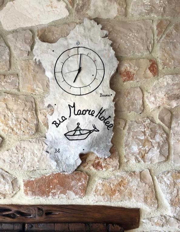 a clock on the side of a stone wall at Hotel Bia Maore in Baunei