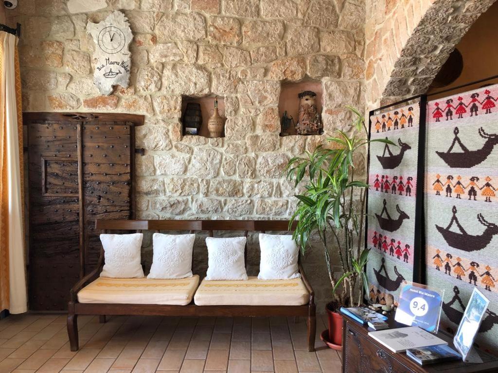 a bench in a room with a stone wall at Hotel Bia Maore in Baunei