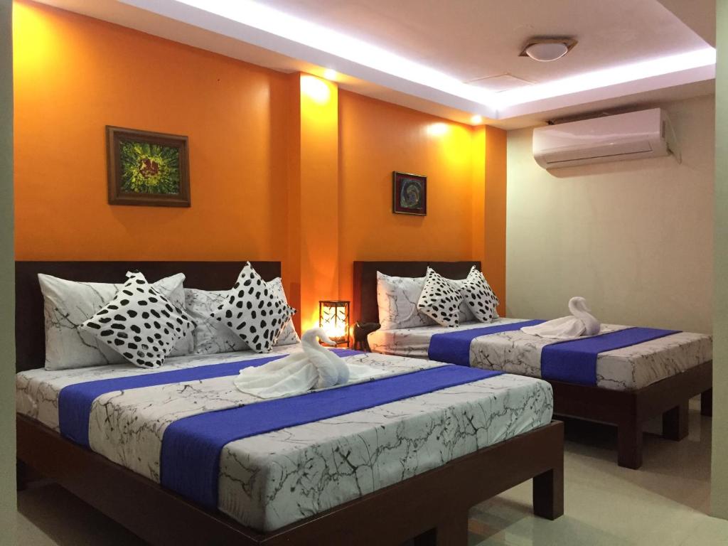 2 Betten in einem Zimmer mit orangefarbenen Wänden in der Unterkunft EA Apartelle - Metro Vigan in Vigan City