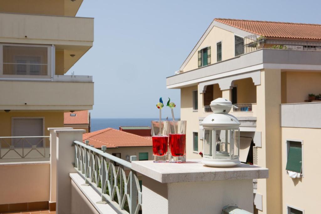 twee glazen rode wijn op een balkon bij Viona Apartments in Alghero
