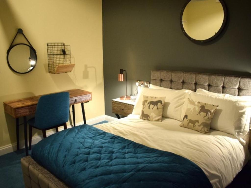 a bedroom with a bed and a desk and a mirror at The Mendip Inn in Binegar