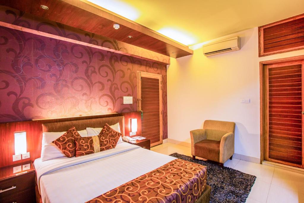 une chambre d'hôtel avec un lit et une chaise dans l'établissement Hotel La Villa Western by Sea Pearl Beach Resort & Spa, à Dhaka