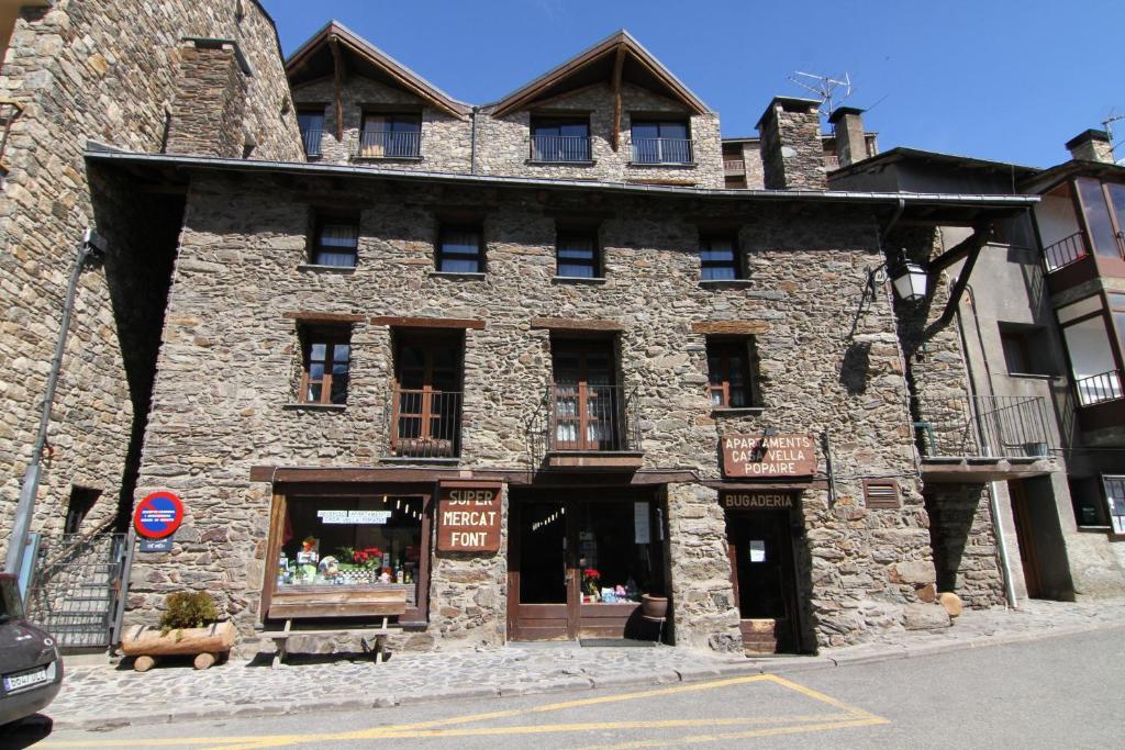 a large stone building with a store in front of it at Apartaments Casa Vella Popaire in Soldeu