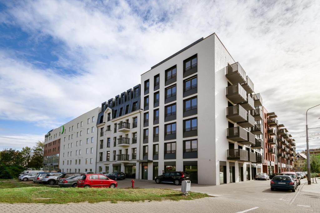 un edificio blanco con coches estacionados en un estacionamiento en King4You Apartments en Breslavia
