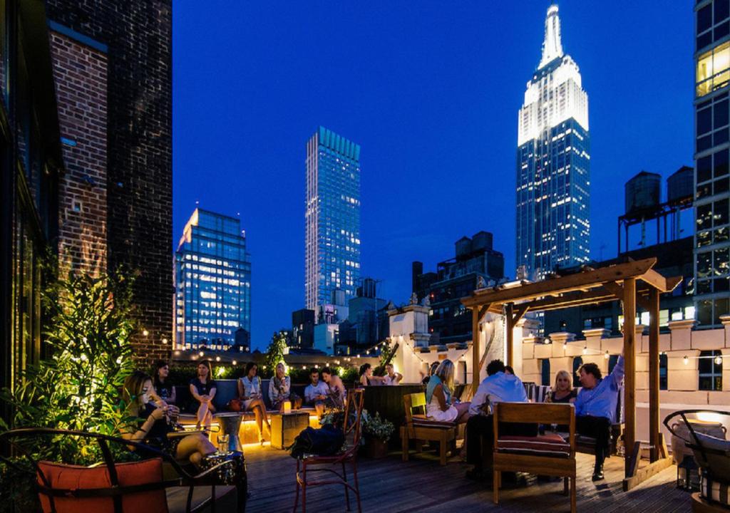 a group of people sitting on the roof of a building at Refinery Hotel - New York in New York